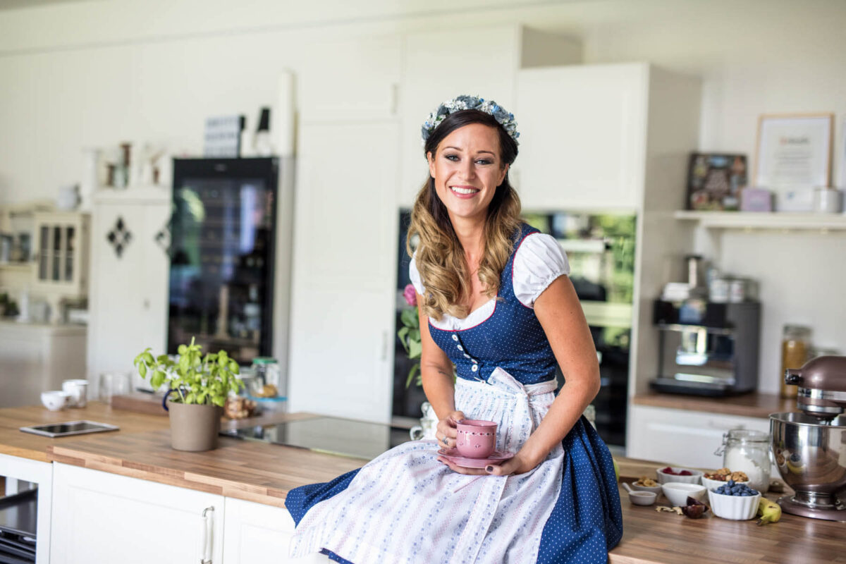 Influencerin CookingCatrin in einem Dirndl in einer schönen Küche.